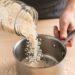 Dry white rice being measured with a pint jar next to a small cooking pot